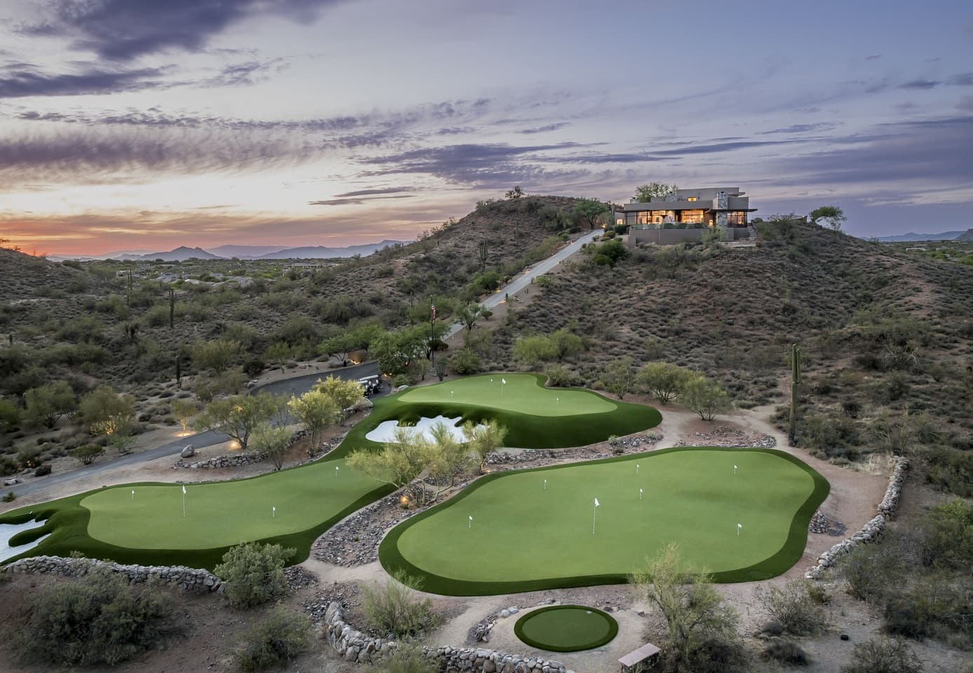 Dusk aerial of the private golf complex below the lit estate