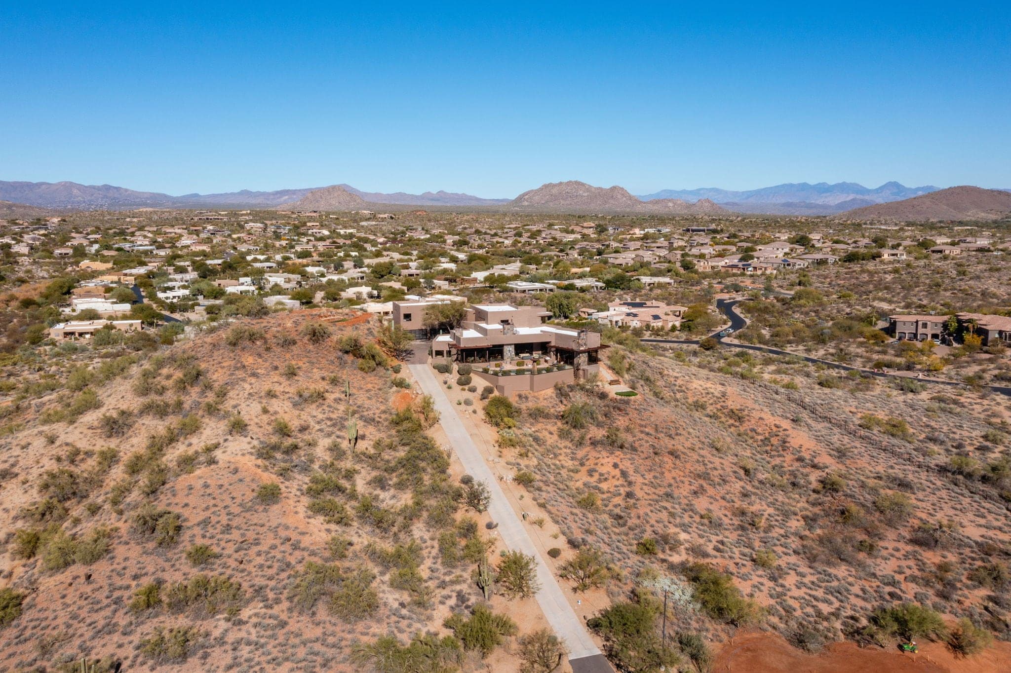 Aerial of the hilltop estate and its private drive at sunset, alone on ten gated acres
