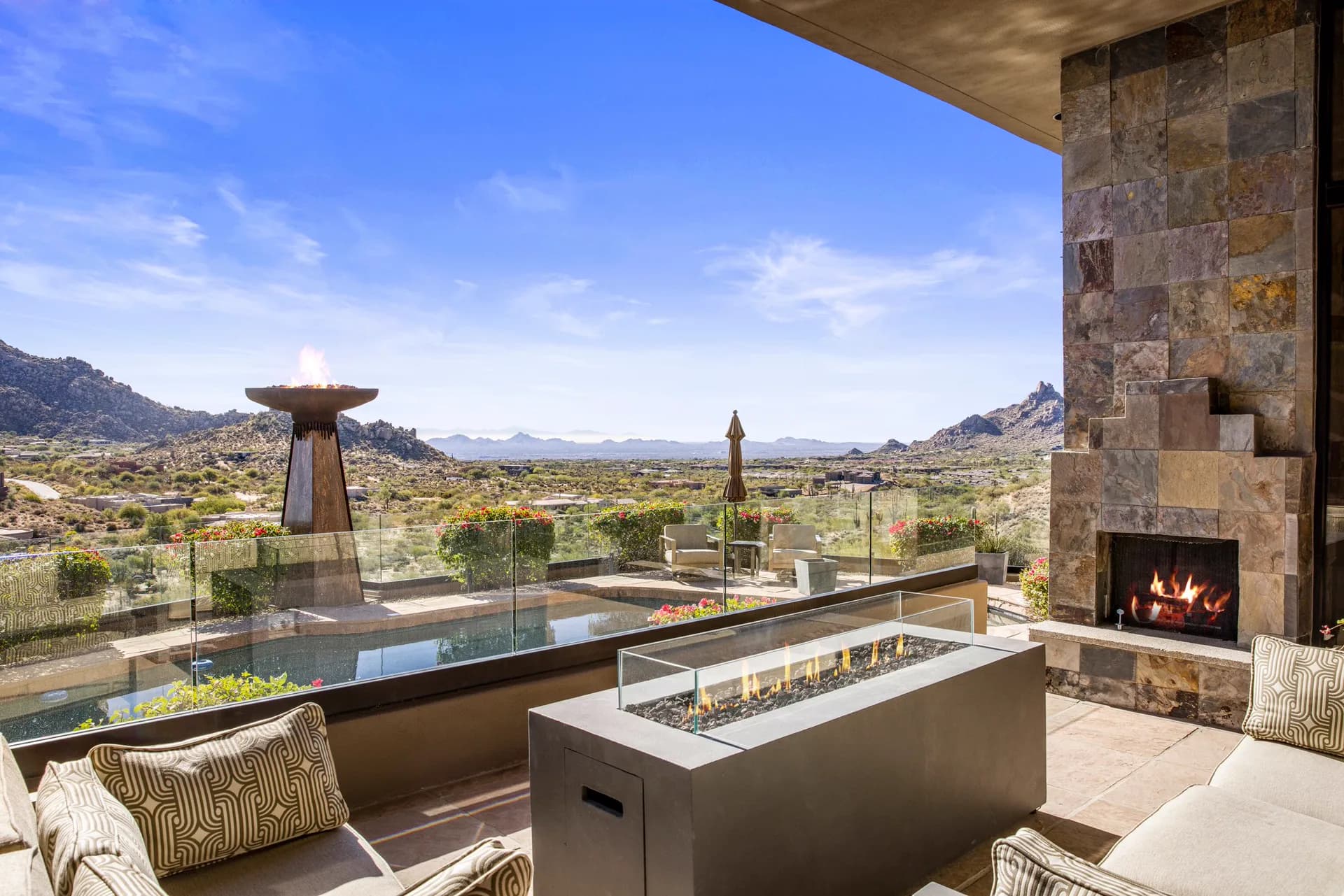 Covered patio with fire table and outdoor fireplace at the pool's edge