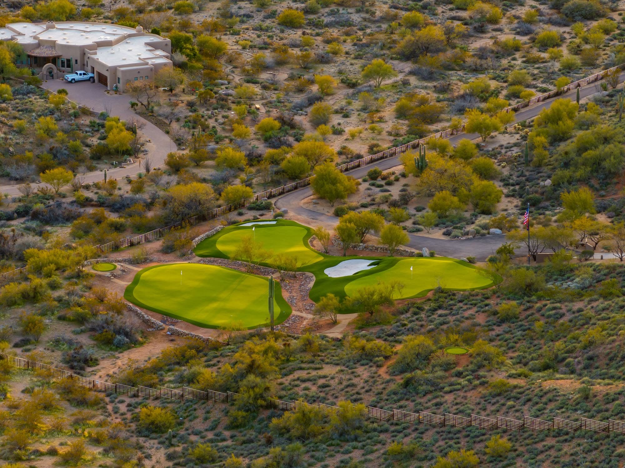 A close aerial on the three-green practice complex at Saguaro Point in golden-hour light
