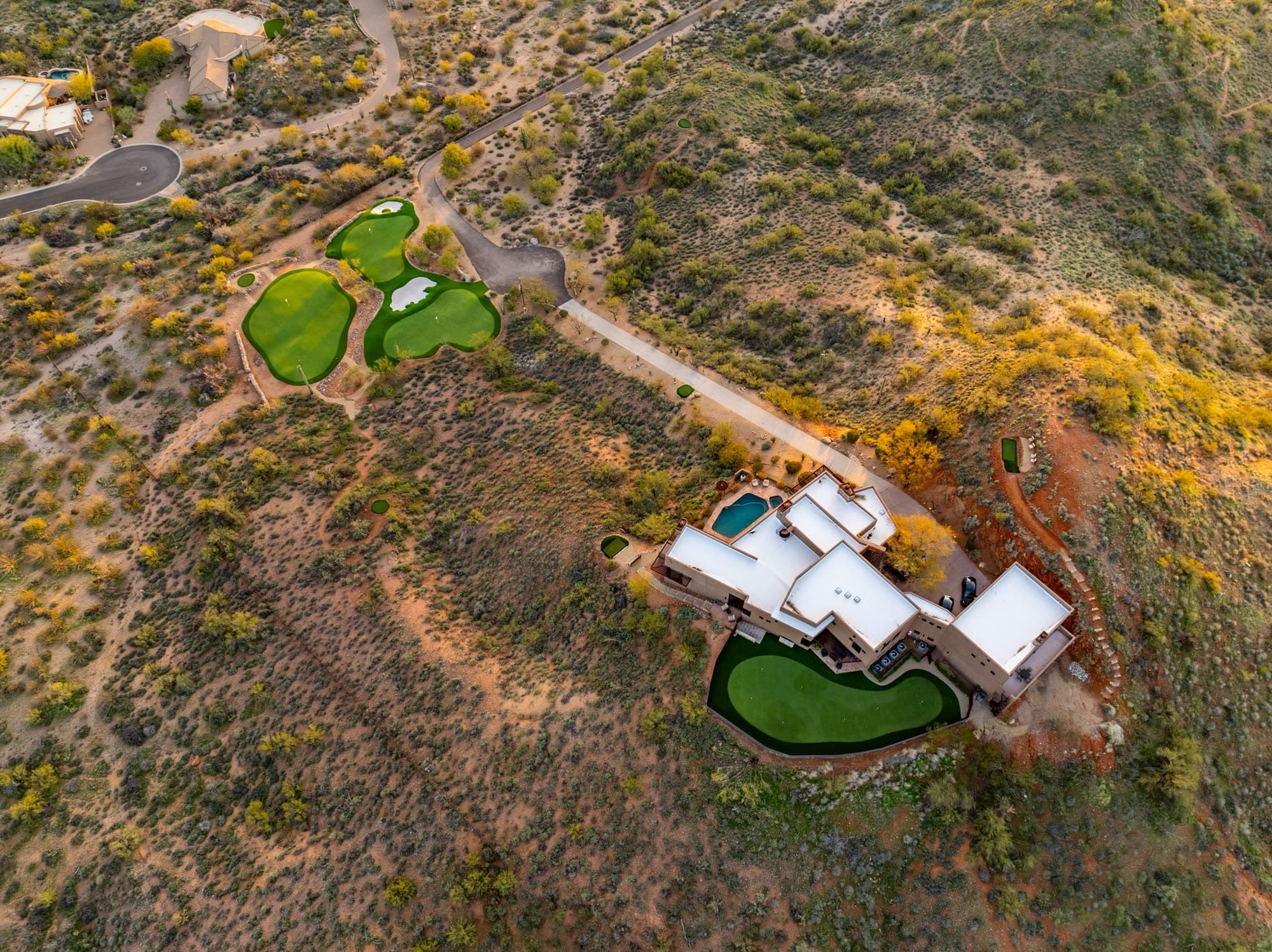 Near-overhead overview of the estate showing the greens, driveway, house, pool, and private green