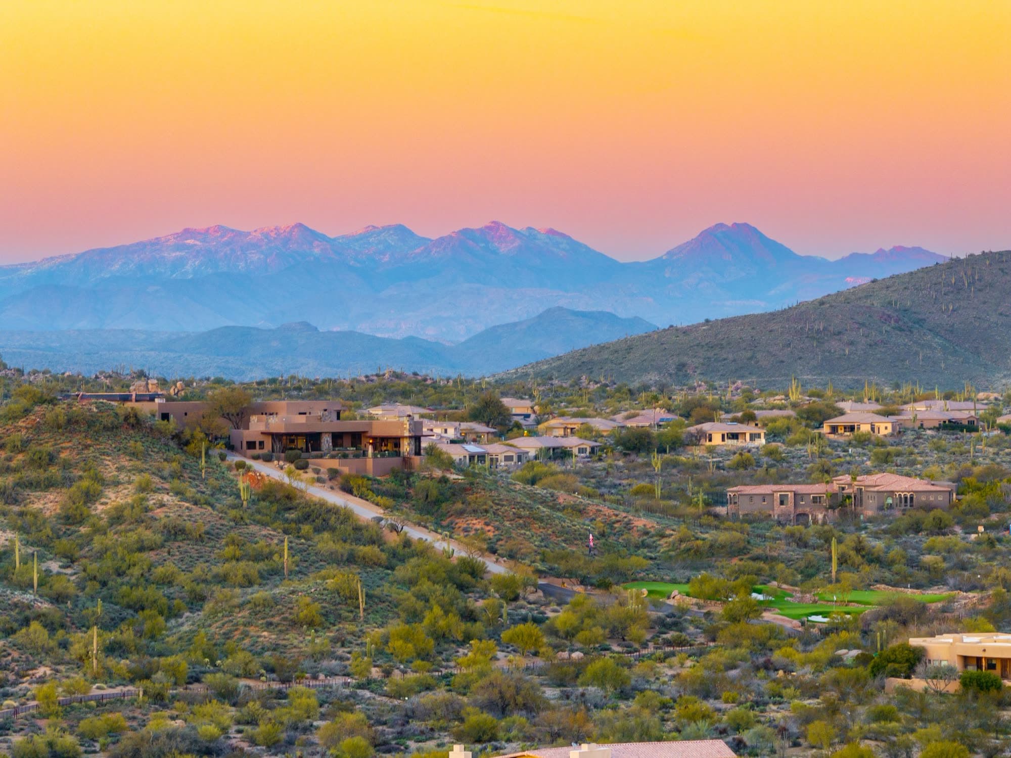 Four Peaks in pastel pink and violet at dusk, the estate sitting mid-frame at left