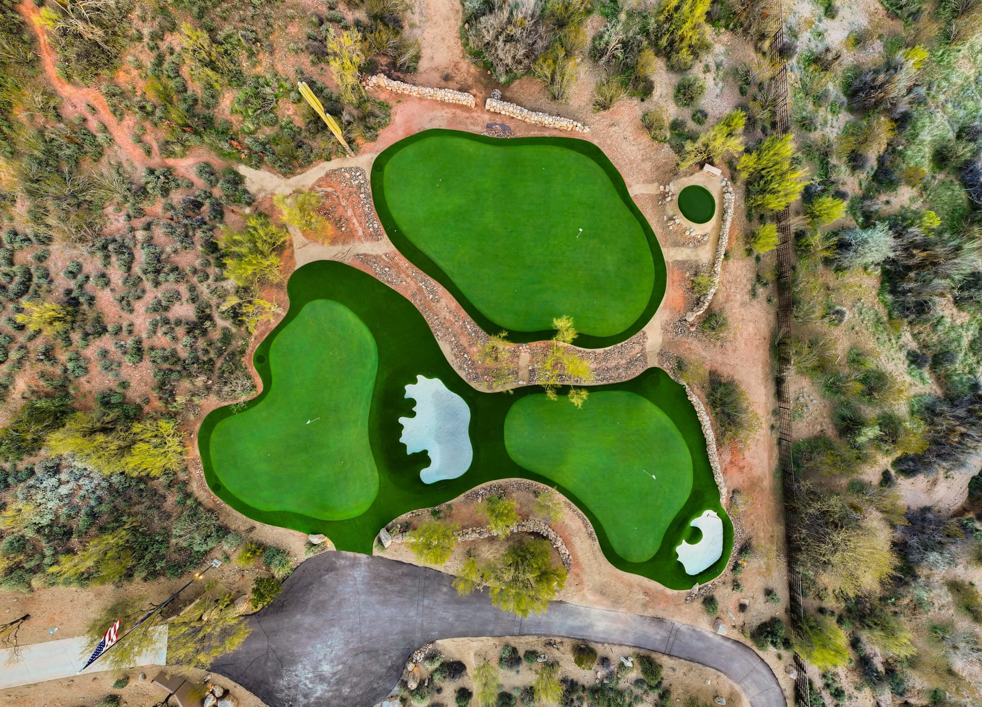 Straight-down aerial of the three private greens and their bunkers, laid out in a clover shape