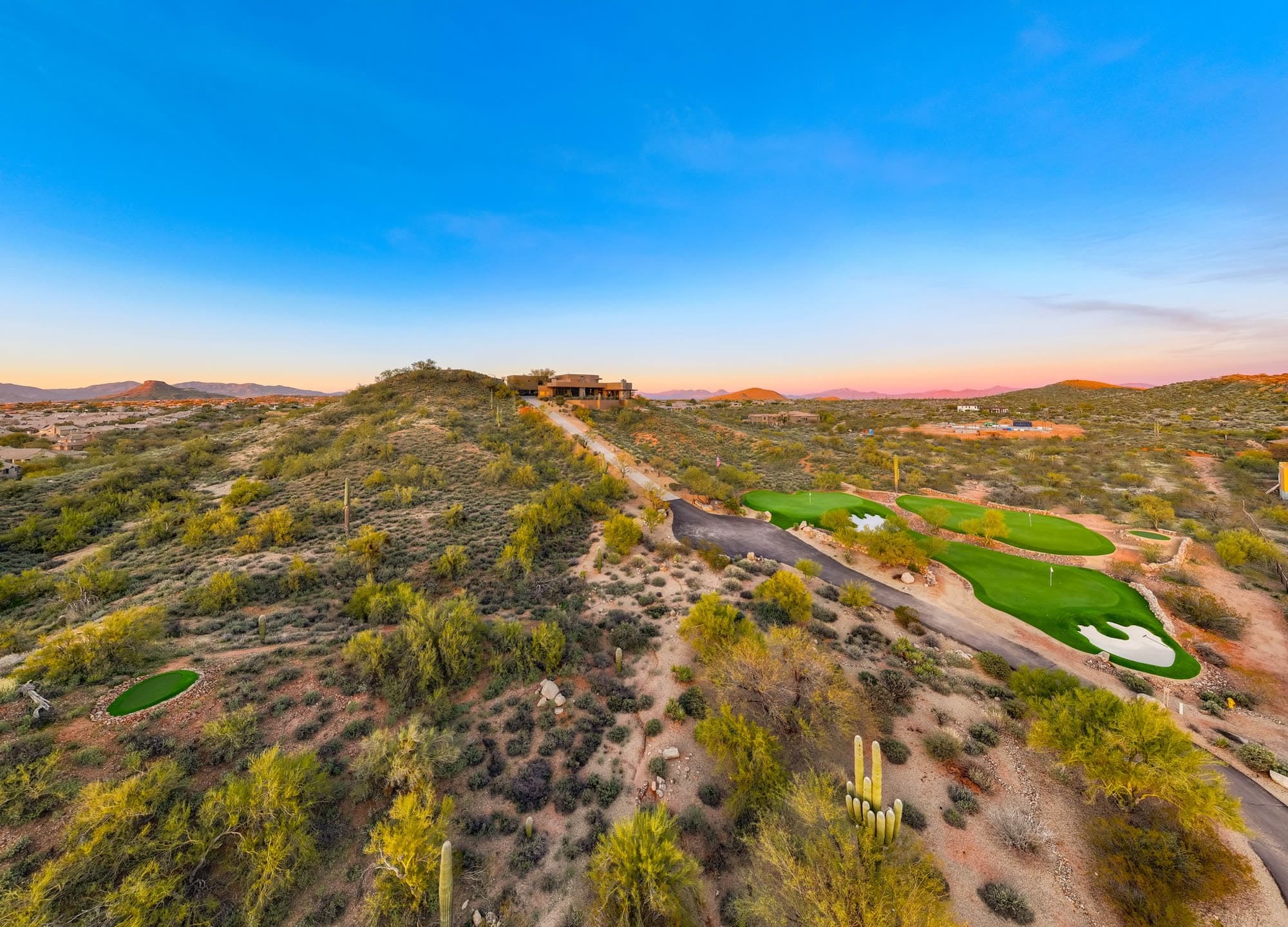 The ridge and greens under a wide dusk sky, the estate small on the crest