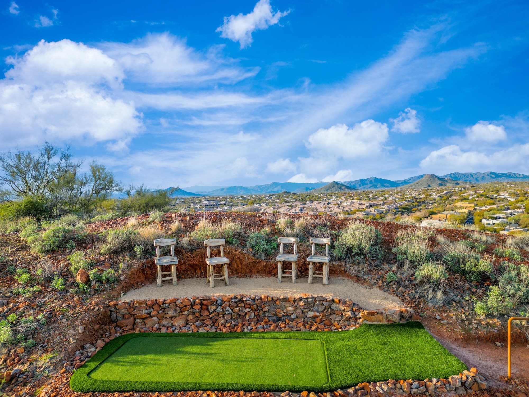 The rectangular tee box at Saguaro Point with four log bar stools, North Scottsdale rooftops spread out behind
